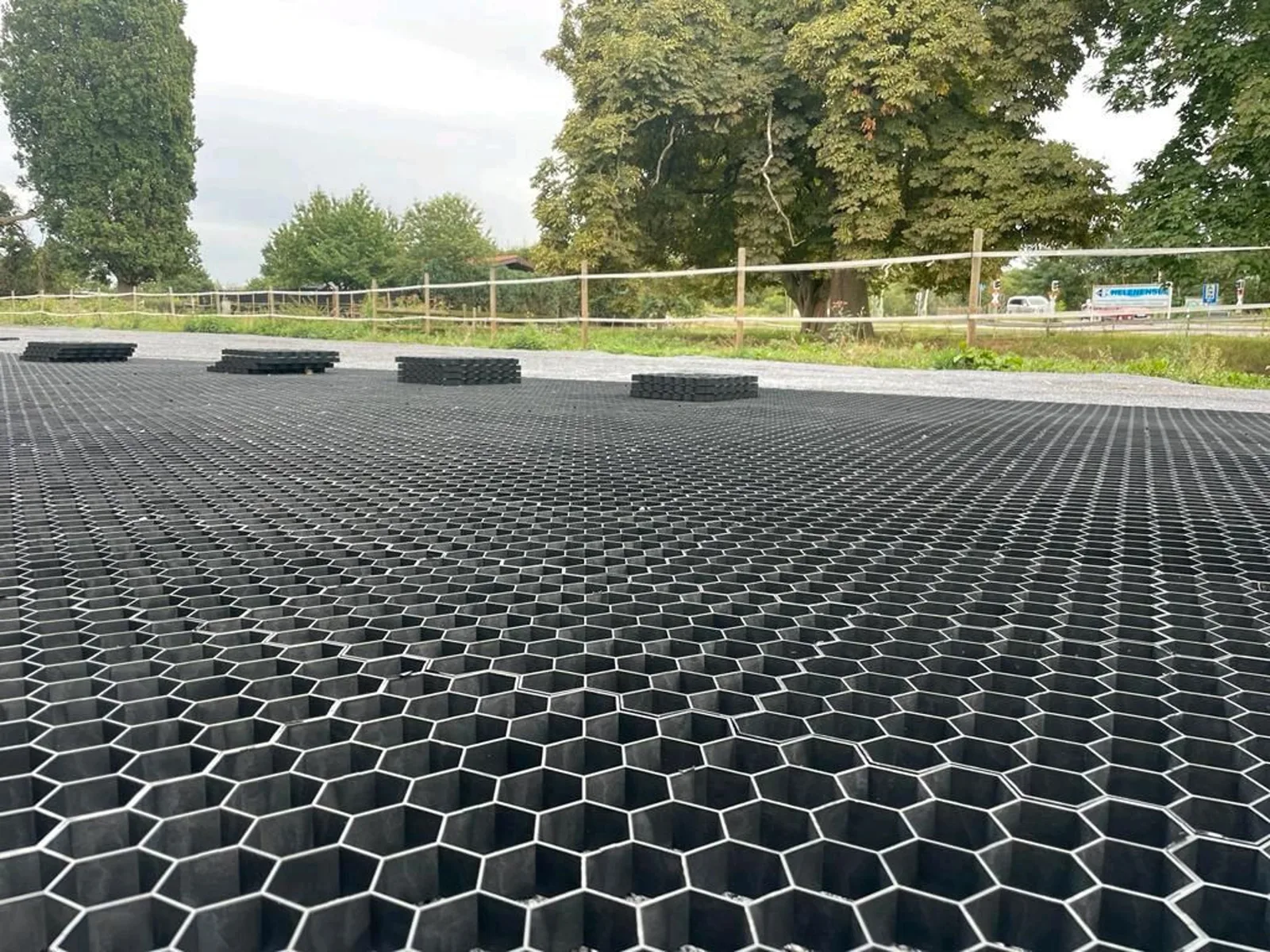 Großflächig verlegte schwarze Paddockplatten vor einer Reitplatzfläche